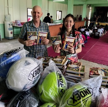 Joel & volunteer distributing helmets & Bibles at Pongsaa Village