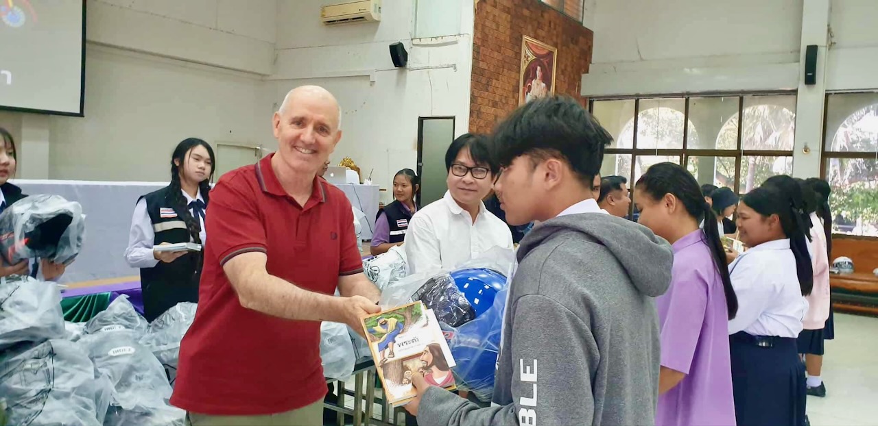 Joel & Dong gifiting helmets & Bibles at a school
